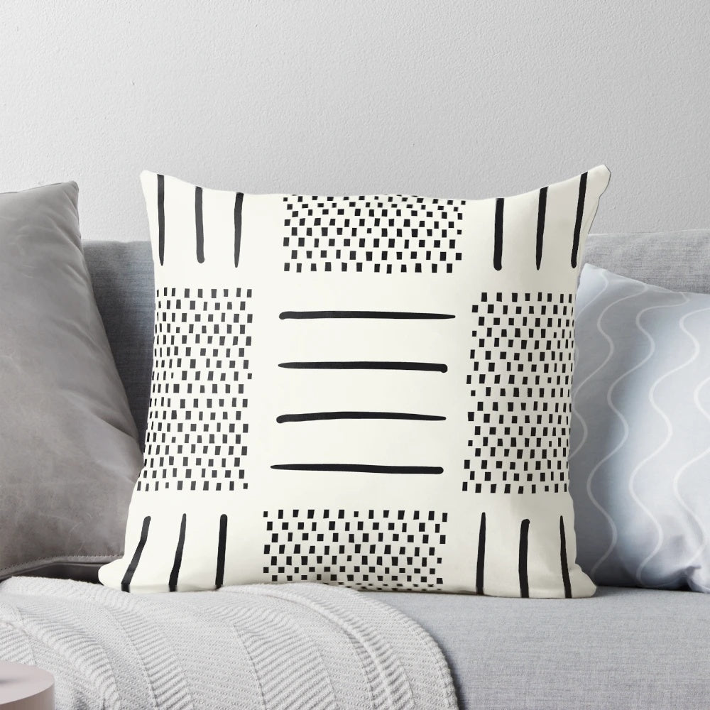A cream and black patchwork pillow with a geometric, bohemian, and tribal design