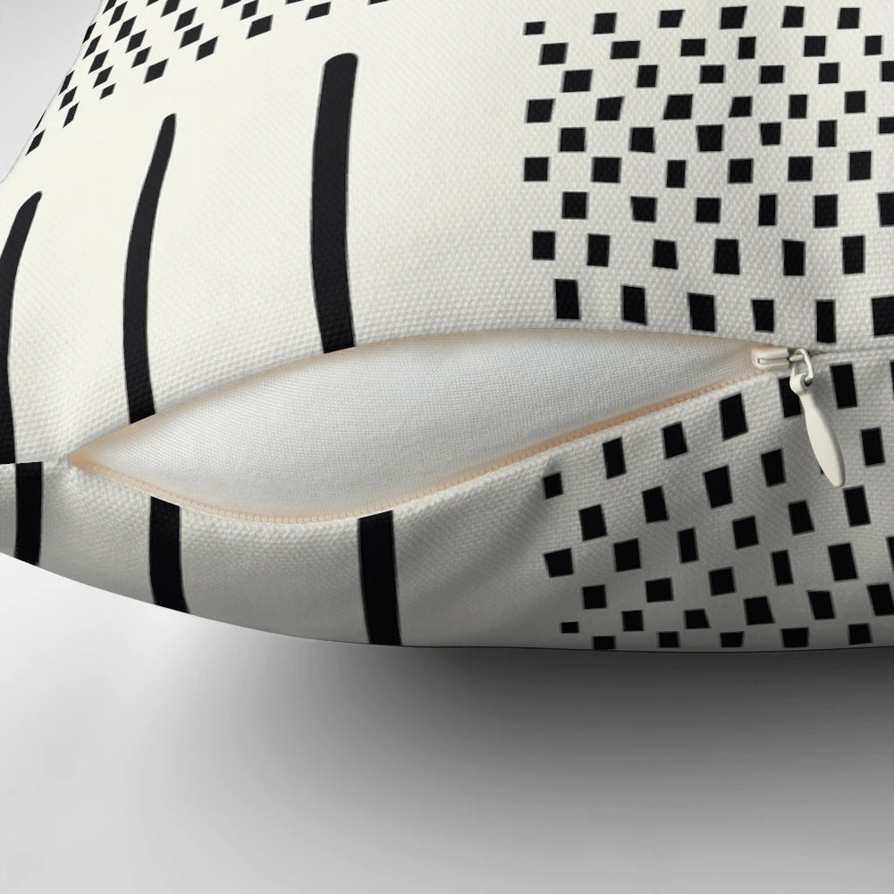 A cream and black patchwork pillow with a geometric, bohemian, and tribal design