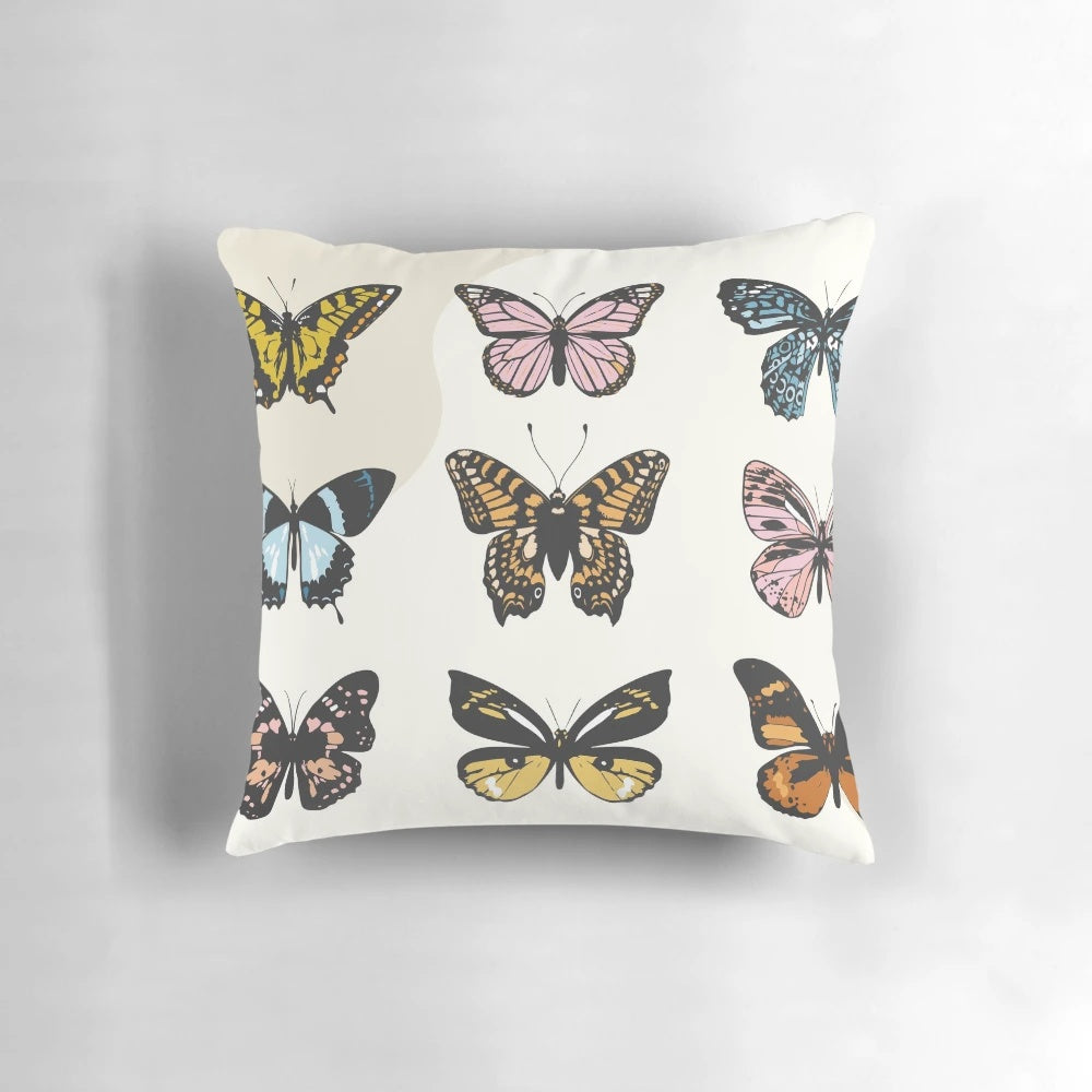 A soft, plush pillow featuring a colorful butterfly sticker pattern in pastel shades of pink, yellow, and mustard.