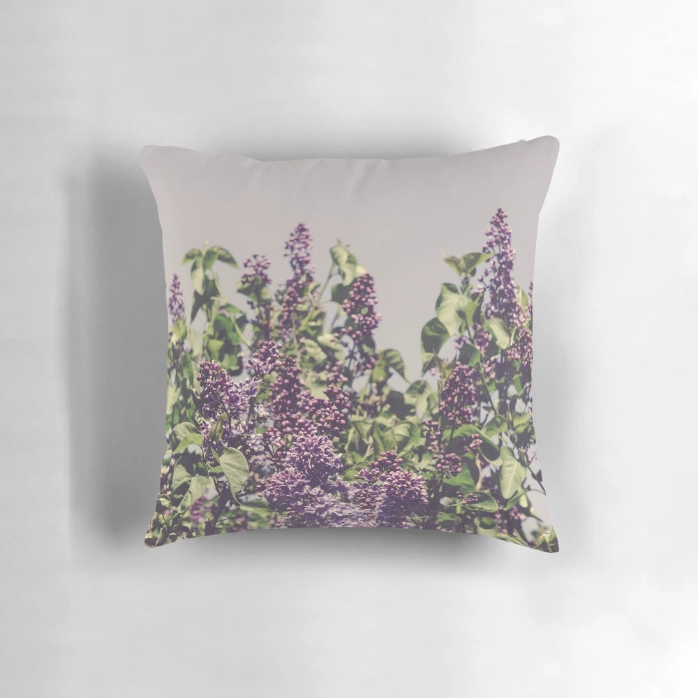 A Boho-style decorative pillow featuring vibrant purple lilacs and a minimalist design