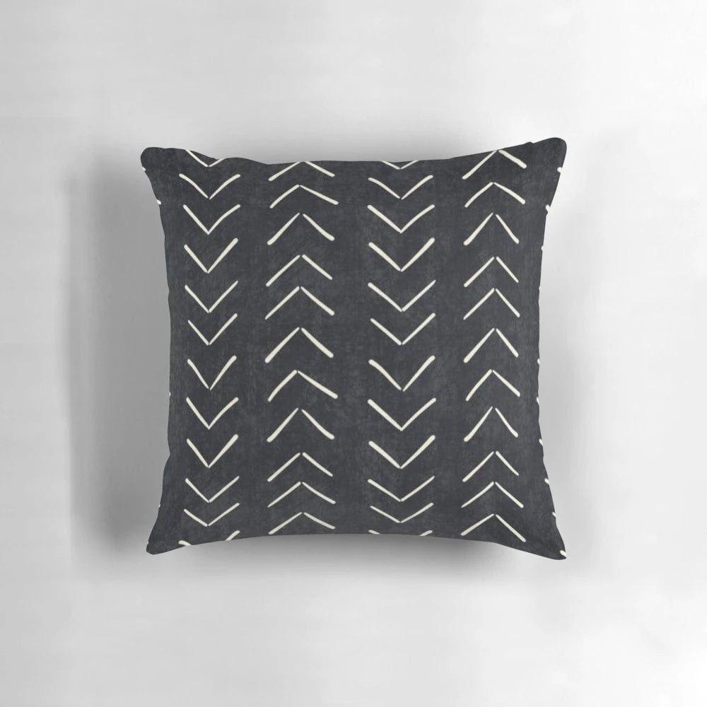 A black and white decorative pillow featuring a tribal-inspired mudcloth pattern with large arrow designs.