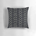A black and white decorative pillow featuring a tribal-inspired mudcloth pattern with large arrow designs.
