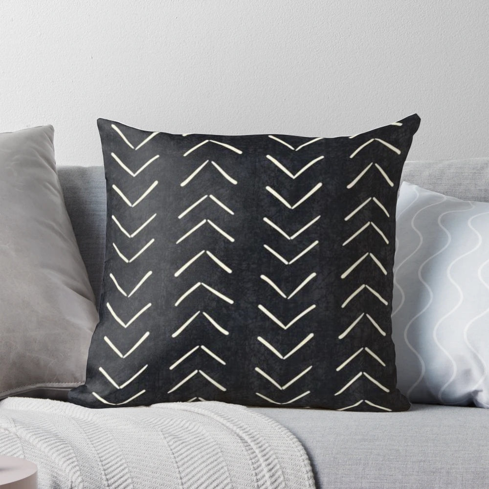 A black and white decorative pillow featuring a tribal-inspired mudcloth pattern with large arrow designs.