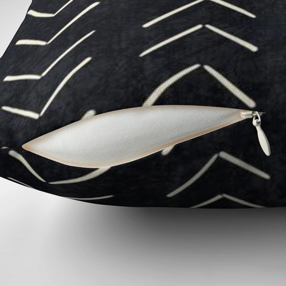 A black and white decorative pillow featuring a tribal-inspired mudcloth pattern with large arrow designs.