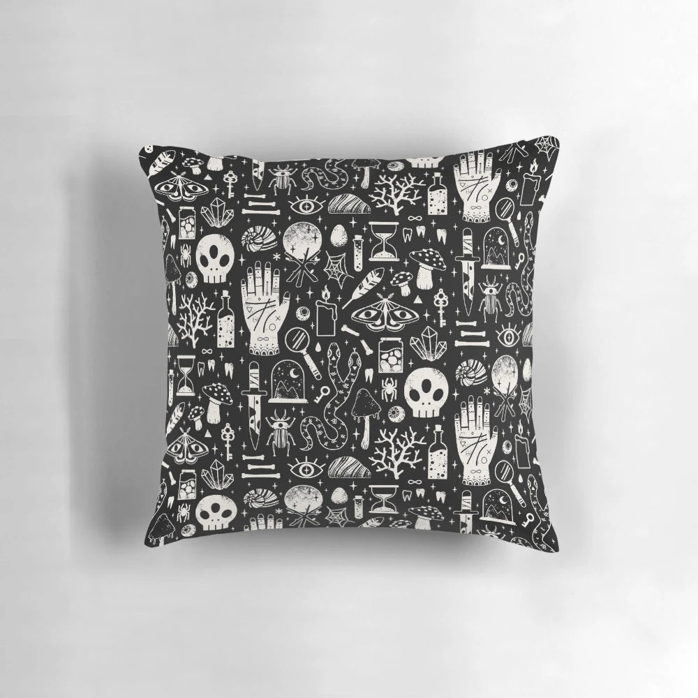 A black and white image of a bone black pillow, featuring a collection of natural elements like skulls, insects, and mushrooms.