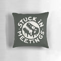 A white pillow with a dinosaur graphic and text reading "Stuck in Meetings
