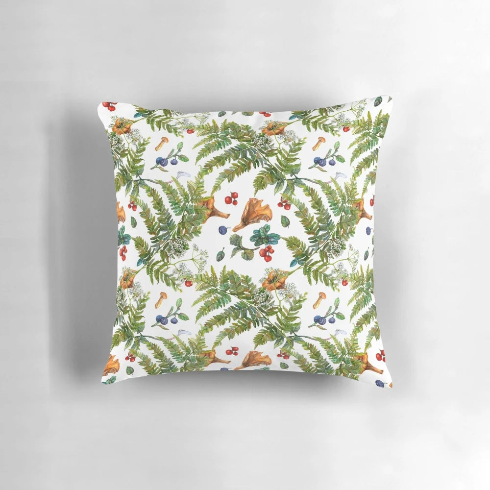 A watercolor painting of forest ferns, berries, and mushrooms on a decorative pillow.