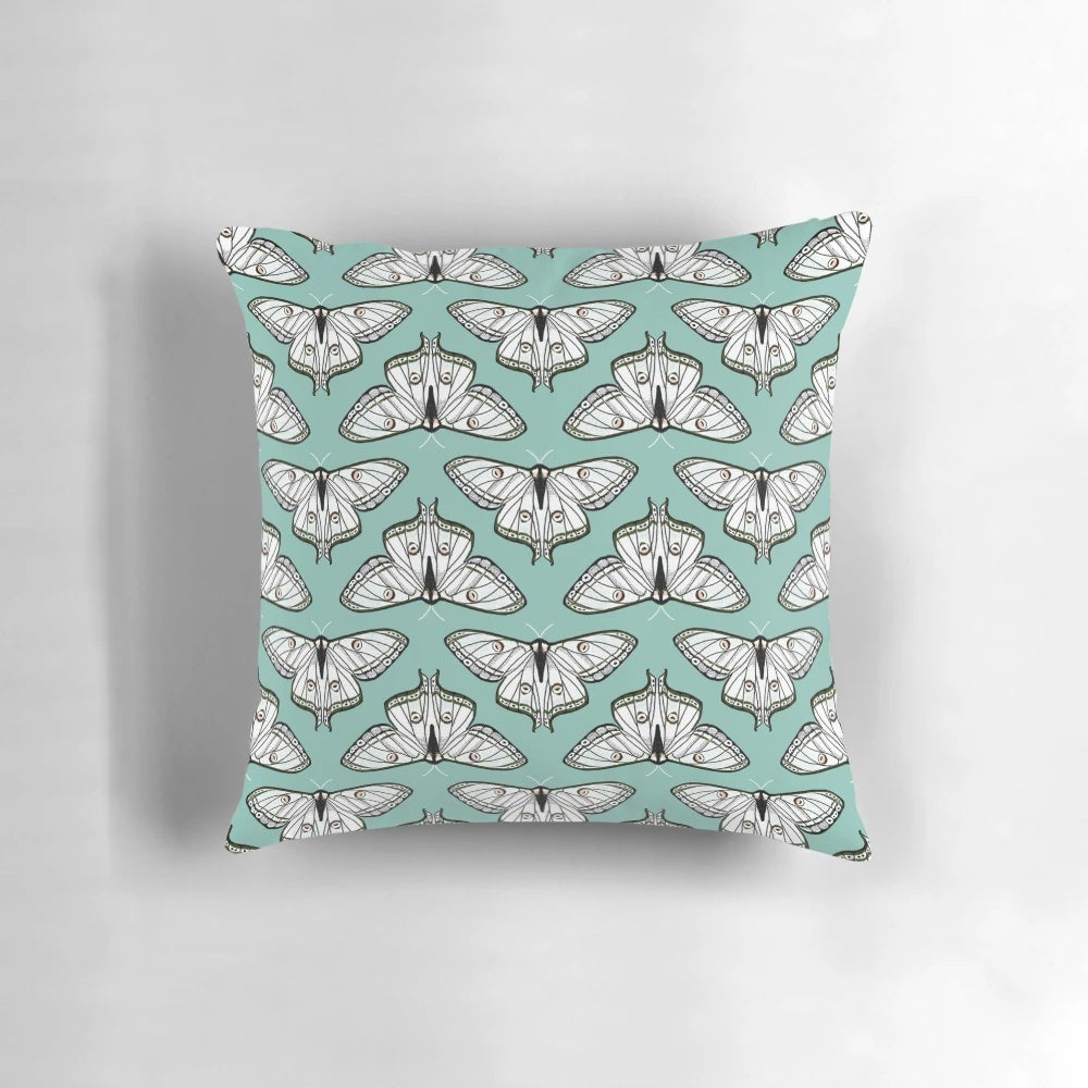 Botanical illustration of a luna moth on a white and green pillow