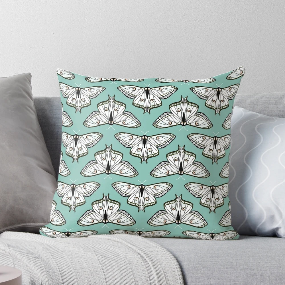 Botanical illustration of a luna moth on a white and green pillow
