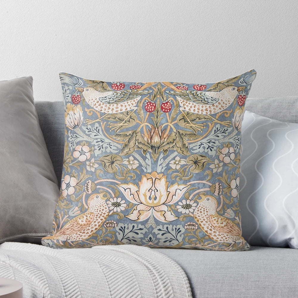 A close-up view of a decorative pillow featuring the iconic "Strawberry Thief" pattern designed by William Morris.
