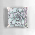 Closeup of a decorative pillow featuring a vibrant arrangement of succulent plants and greenery.