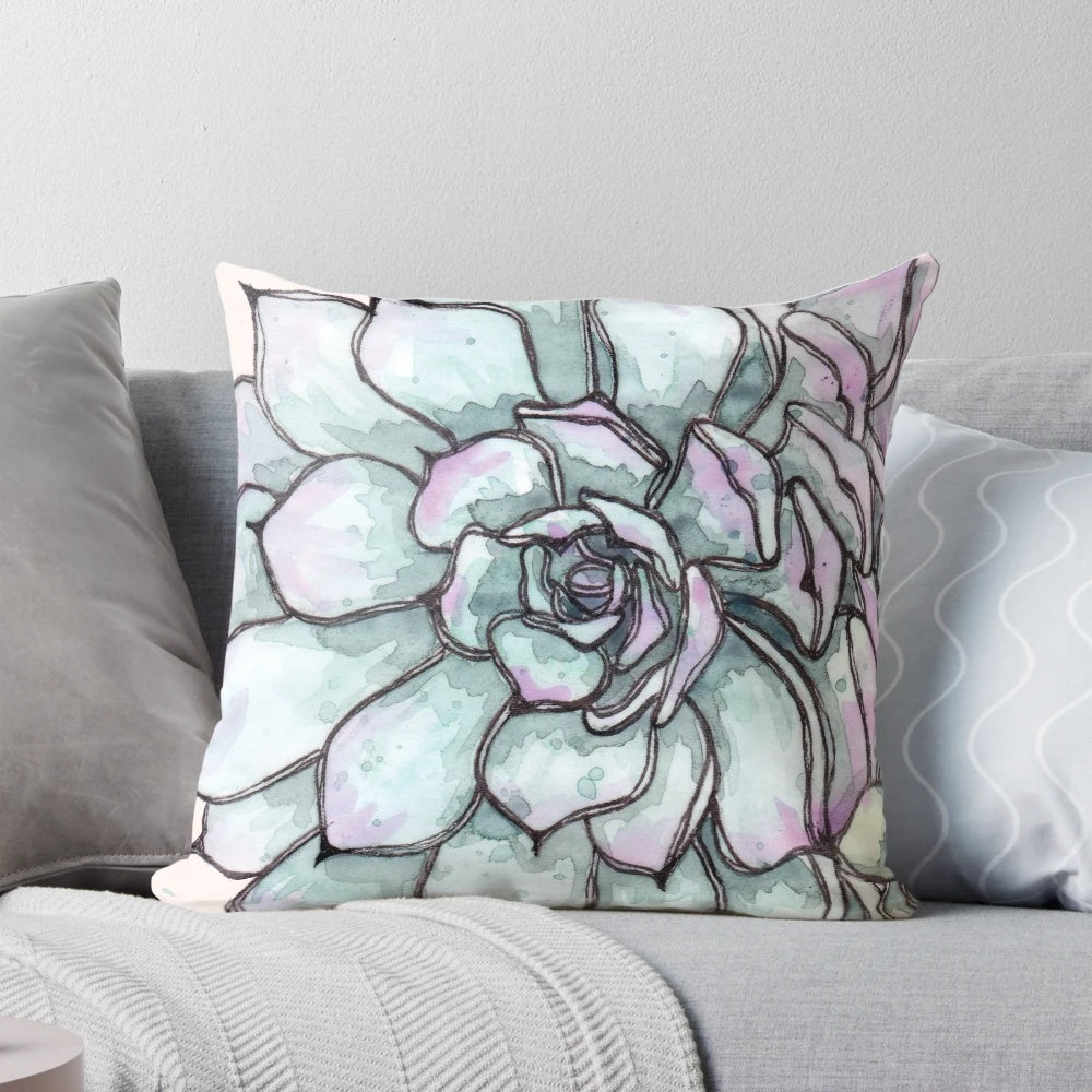 Closeup of a decorative pillow featuring a vibrant arrangement of succulent plants and greenery.