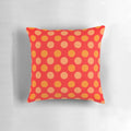 Bright orange and red polka dot patterned throw pillow with a geometric design on a red background.