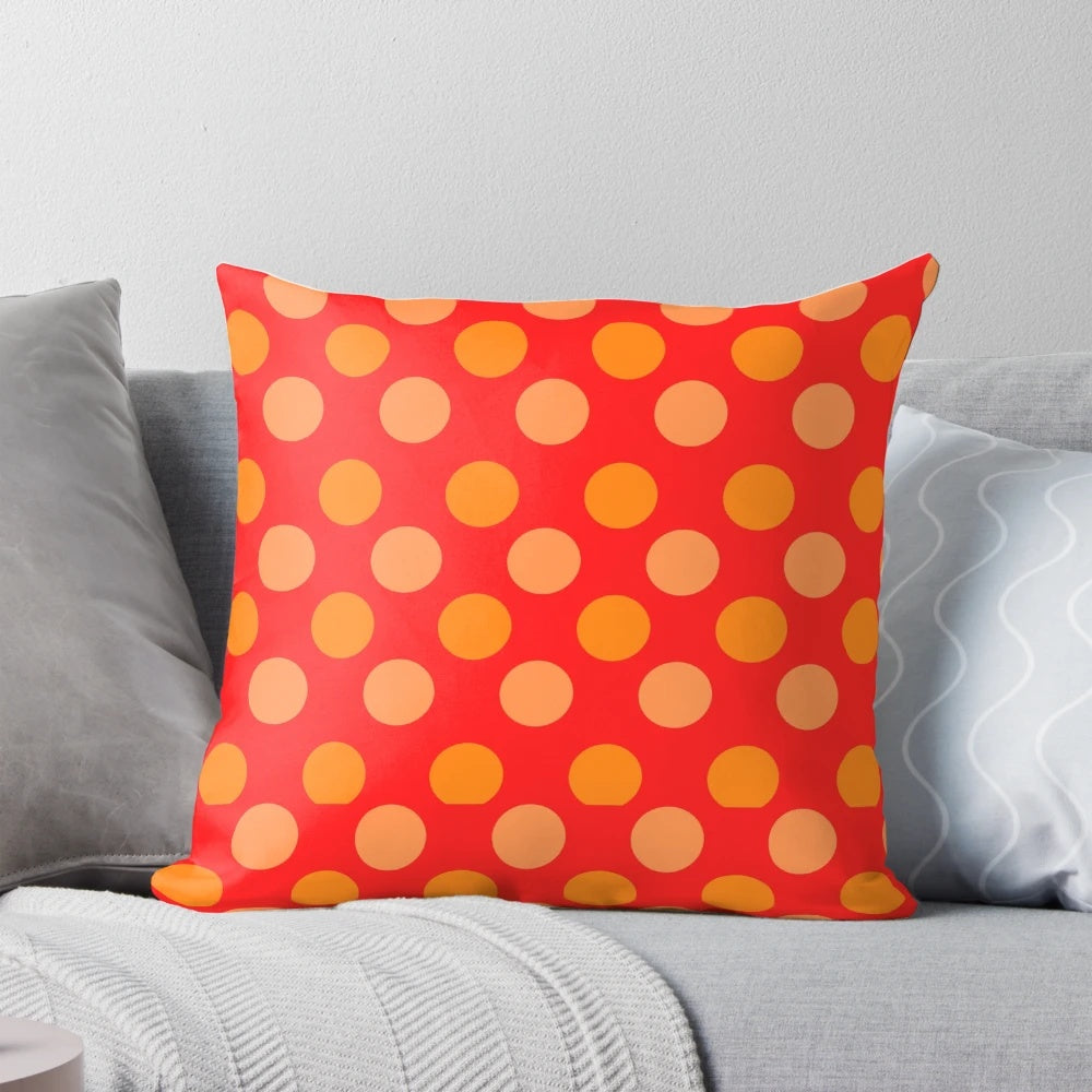 Bright orange and red polka dot patterned throw pillow with a geometric design on a red background.