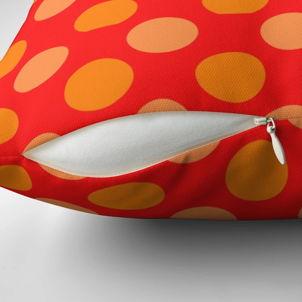 Bright orange and red polka dot patterned throw pillow with a geometric design on a red background.