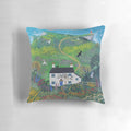 A decorative pillow featuring a serene lighthouse scene against a backdrop of a white cottage, lush gardens, and the sea.