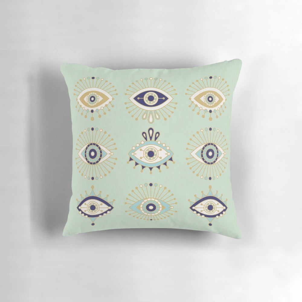 Decorative throw pillow with a vibrant evil eye design in shades of blue, gold, and mint.