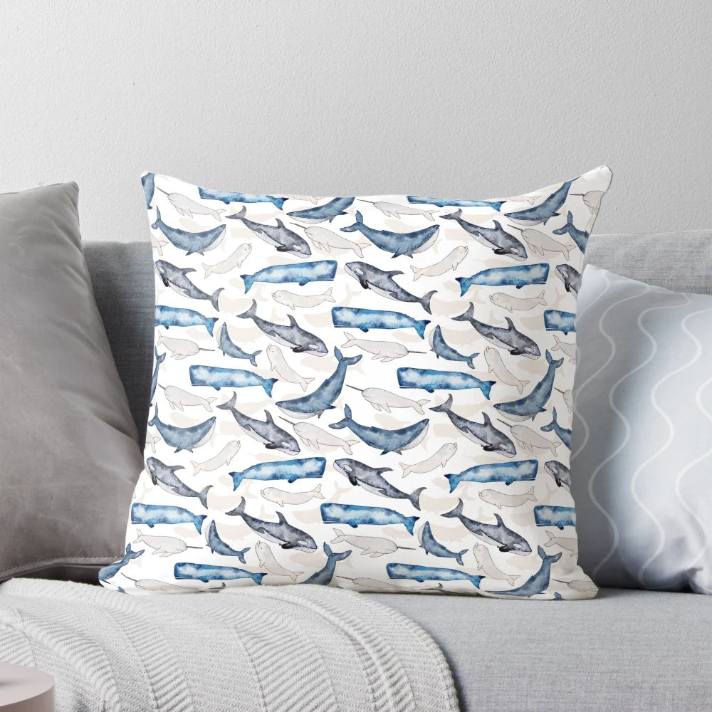 Vibrant watercolor painting of humpback, orca, narwhal, and sperm whales on a blue and turquoise beach-themed throw pillow.