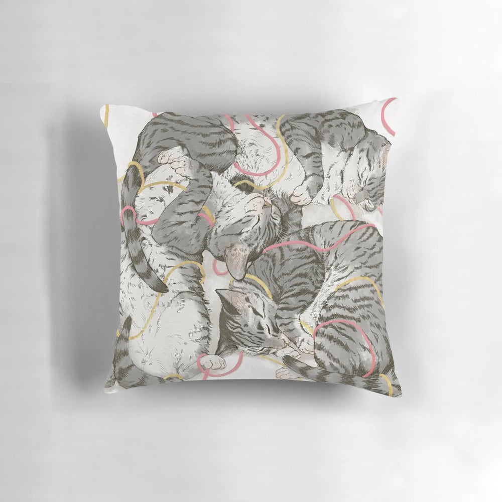 A soft and plush pillow featuring a watercolor design of cats in shades of grey, pink, and rose gold.