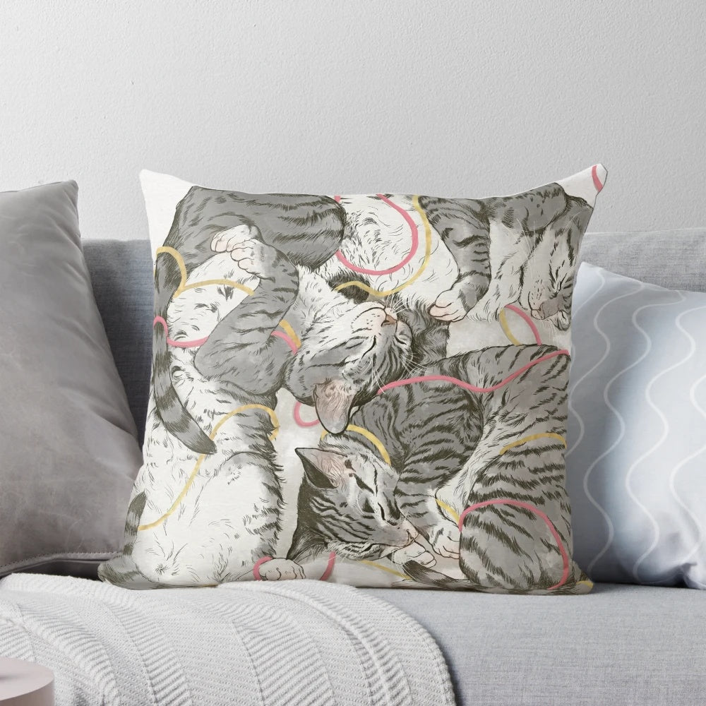 A soft and plush pillow featuring a watercolor design of cats in shades of grey, pink, and rose gold.