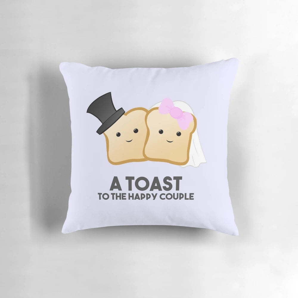 A white and gray accent pillow with the text "A TOAST to the happy couple" as a pun.
