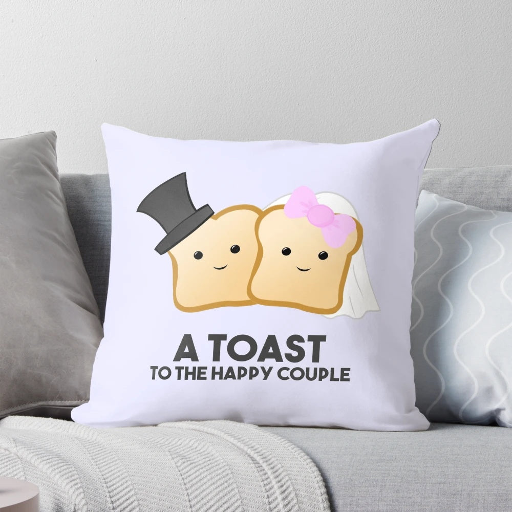 A white and gray accent pillow with the text "A TOAST to the happy couple" as a pun.