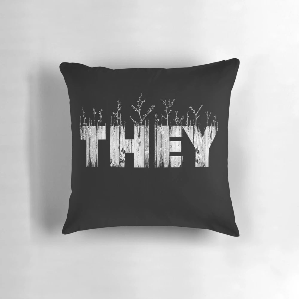 A cozy, nature-themed pillow with the text 'THEY' printed on it, representing gender identity and self-expression.