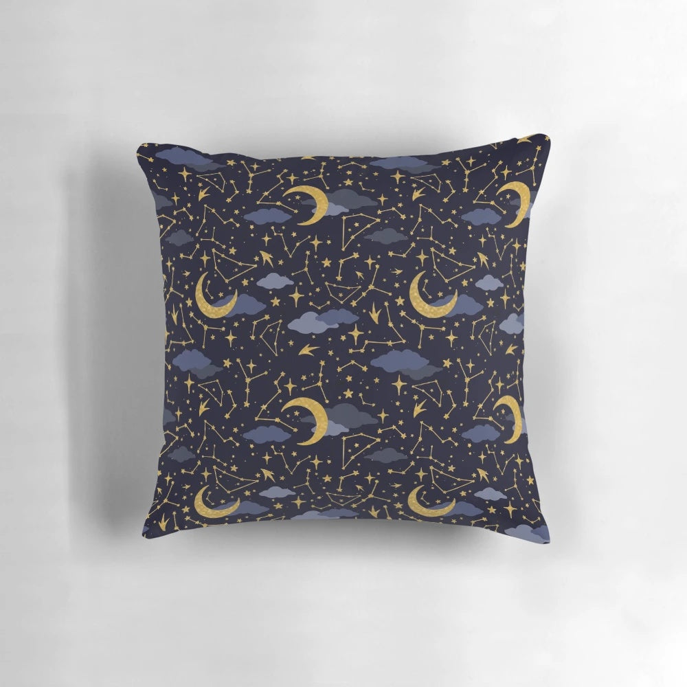 A decorative pillow featuring a cosmic design of stars, moons, and galaxies in gold and dark blue.
