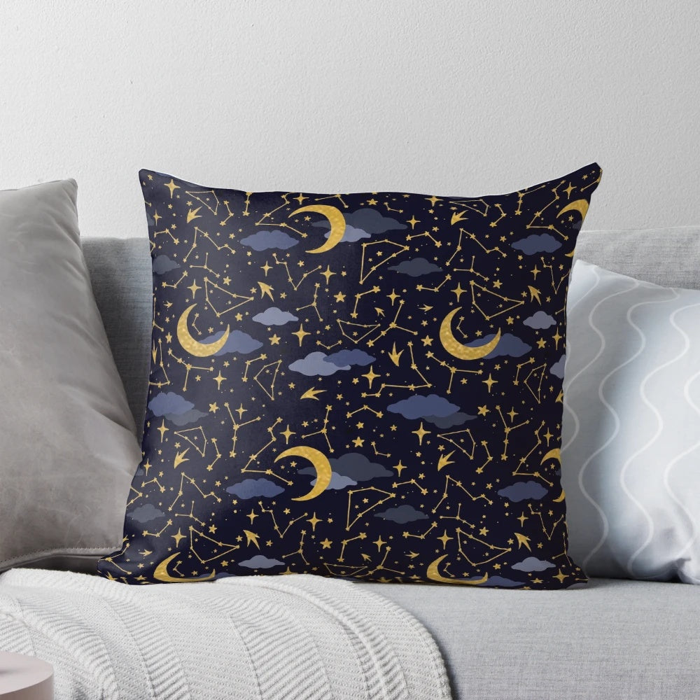 A decorative pillow featuring a cosmic design of stars, moons, and galaxies in gold and dark blue.