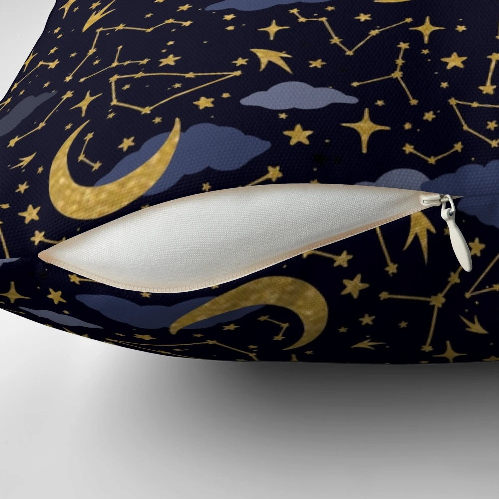 A decorative pillow featuring a cosmic design of stars, moons, and galaxies in gold and dark blue.