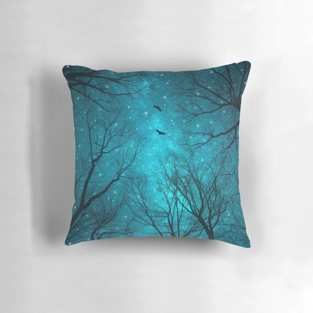 A decorative throw pillow featuring a starry night sky, galaxy, and silhouetted trees against a mint teal background.