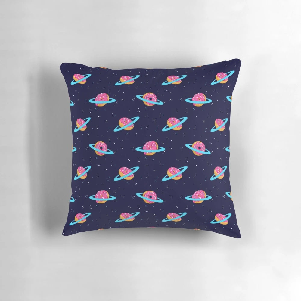 A plush, galaxy-inspired pillow featuring a whimsical design of Saturn's rings made of sweet, chocolate-coated doughnuts against a backdrop of stars.