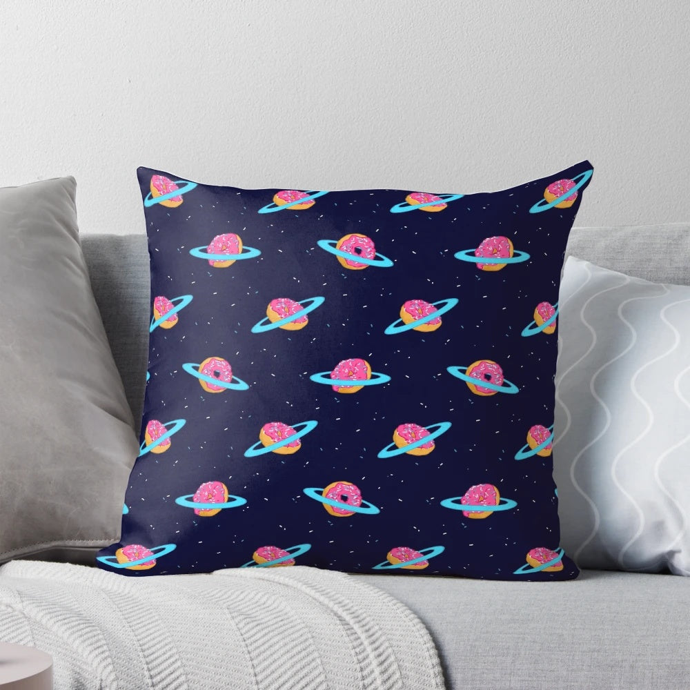 A plush, galaxy-inspired pillow featuring a whimsical design of Saturn's rings made of sweet, chocolate-coated doughnuts against a backdrop of stars.