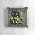 A black cat with vibrant flowers decorating a cozy throw pillow