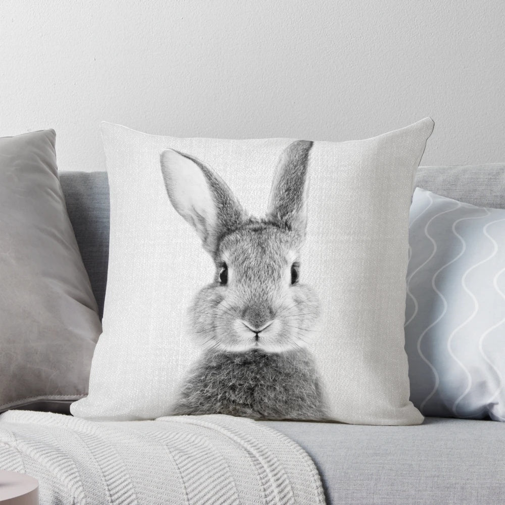 Black and white portrait illustration of a playful rabbit on a soft, plush pillow.