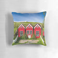 A cozy pillow featuring a whimsical illustration of traditional red elf houses in the Icelandic countryside