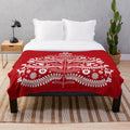 Scandinavian-inspired white Christmas tree with snowflakes, deer, and folk art designs on a red plush blanket