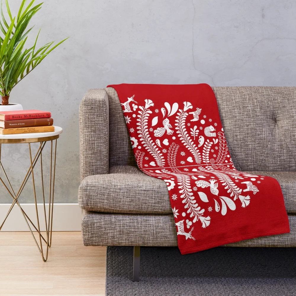 Scandinavian-inspired white Christmas tree with snowflakes, deer, and folk art designs on a red plush blanket