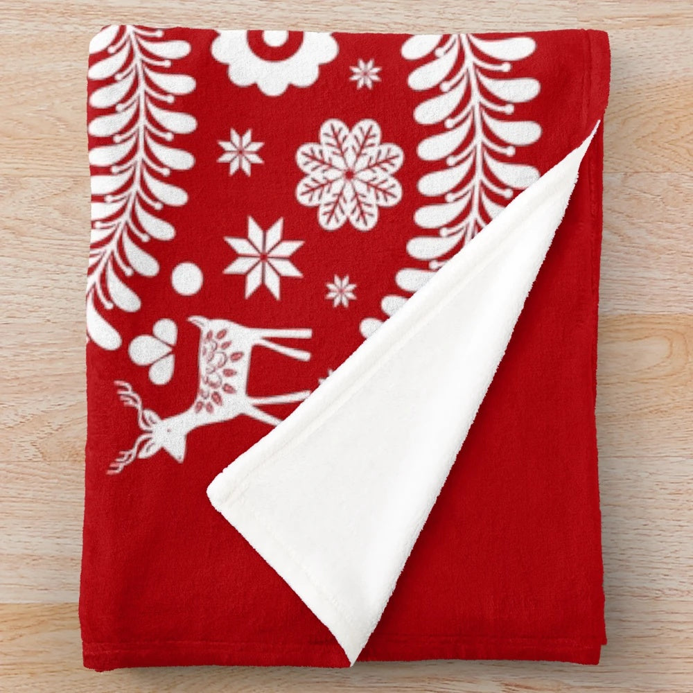 Scandinavian-inspired white Christmas tree with snowflakes, deer, and folk art designs on a red plush blanket