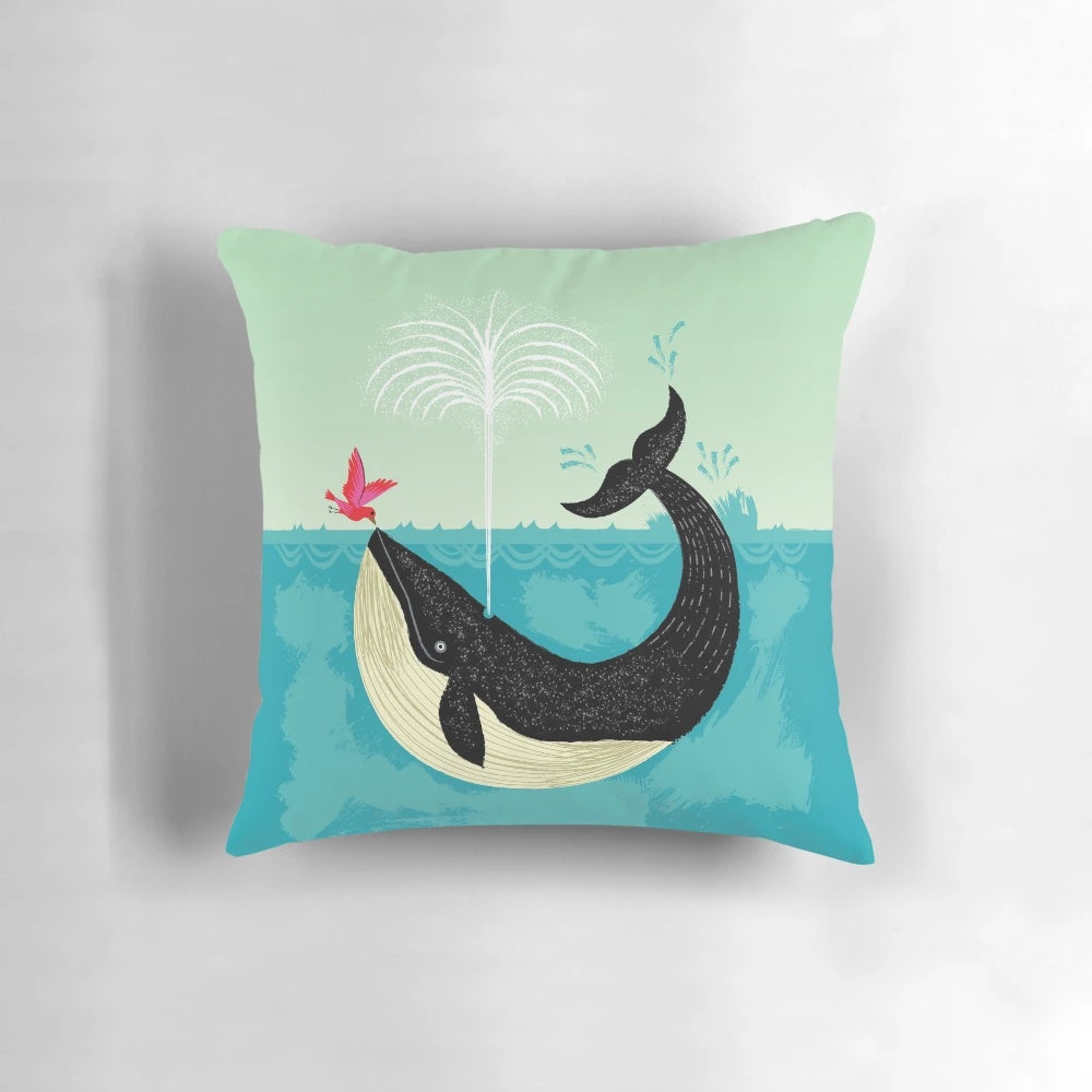 Decorative pillow featuring a whimsical illustration of a whale and bird in a coastal scene
