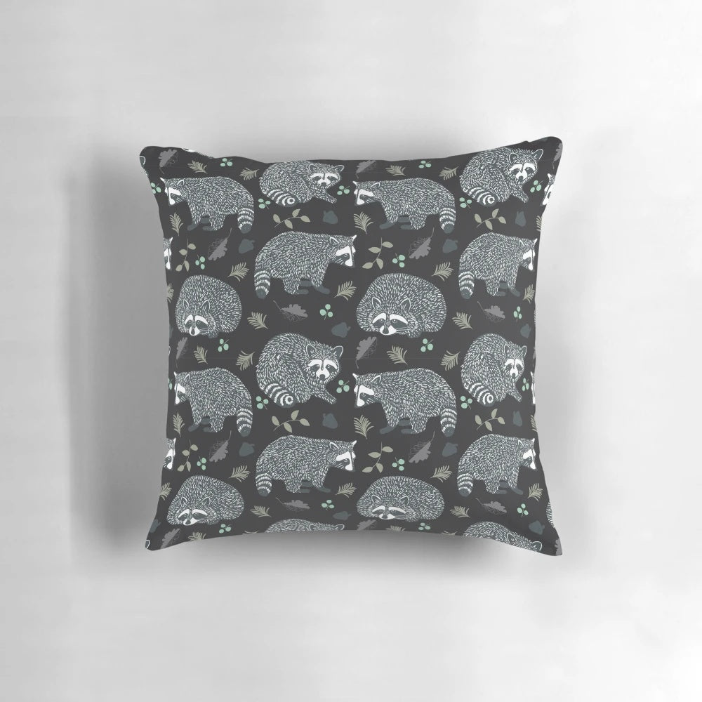 Decorative throw pillow with a whimsical repeat pattern of cute raccoons in a woodland setting