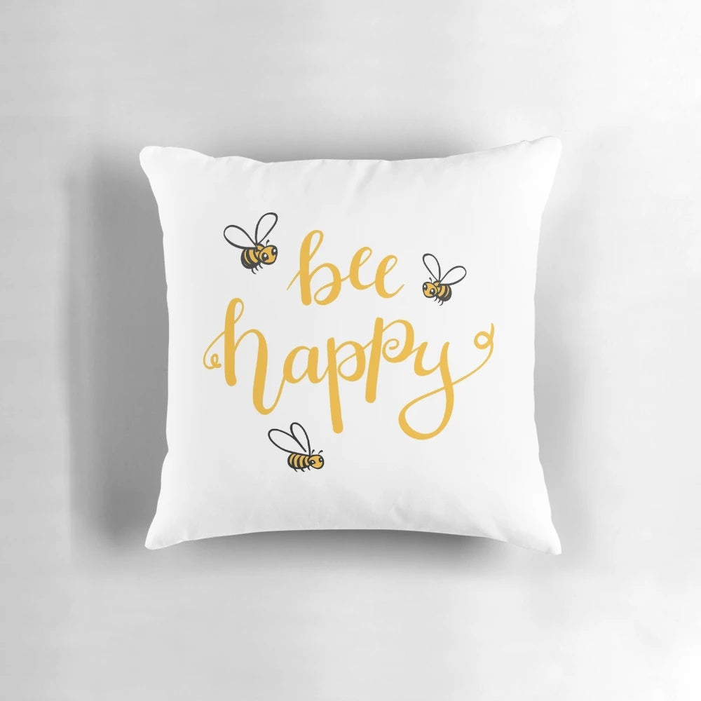 Bright yellow bee-themed pillow with "Bee Happy" lettering