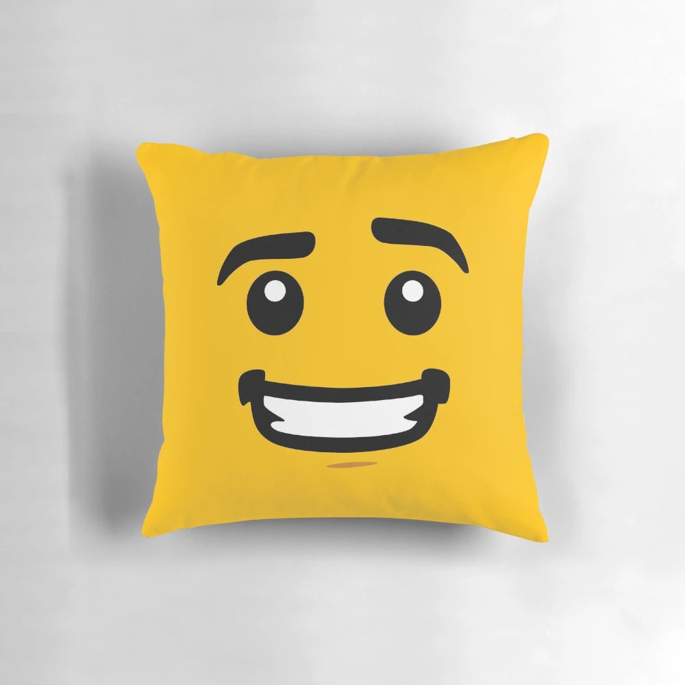 A bright yellow pillow featuring a smiling lego-style face design