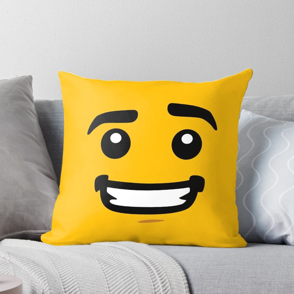A bright yellow pillow featuring a smiling lego-style face design