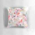 A pink and teal watercolor floral pattern on a plush, chic throw pillow.