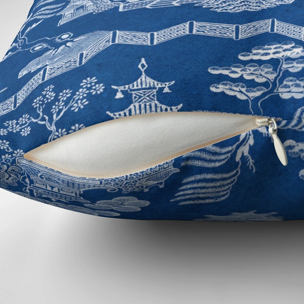 Chinoiserie-style blue and white decorative pillow with pagoda, crane, and boat motif