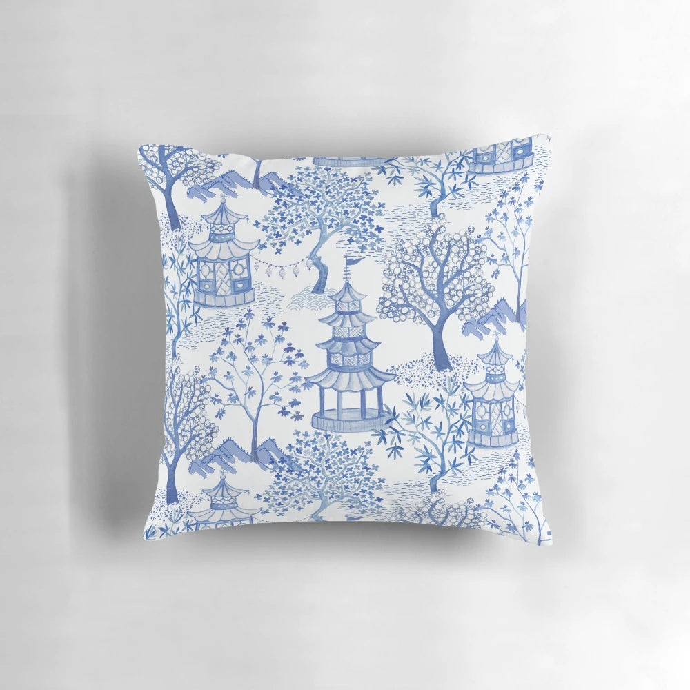 A blue and white throw pillow featuring a chinoiserie-style pagoda forest pattern.