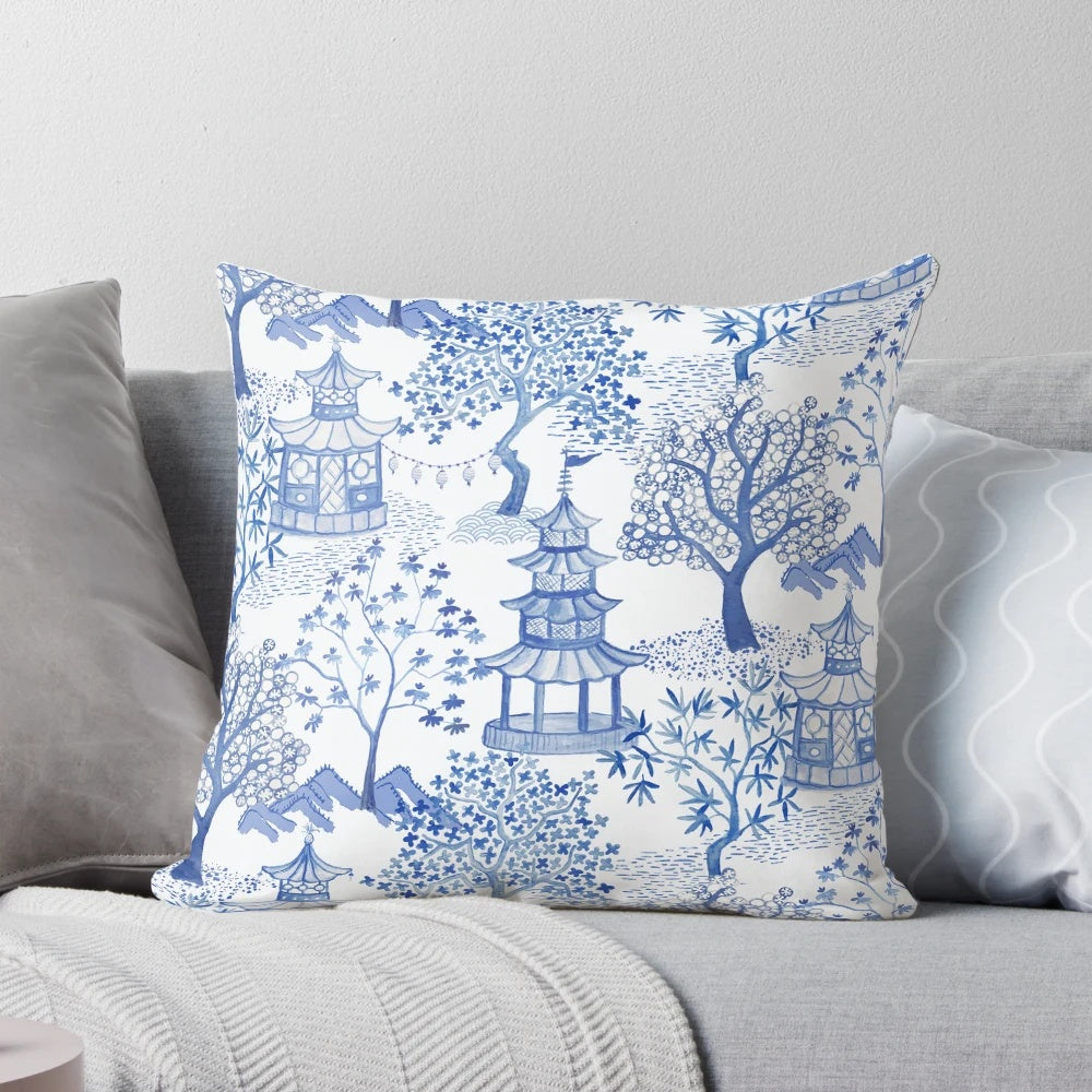 A blue and white throw pillow featuring a chinoiserie-style pagoda forest pattern.