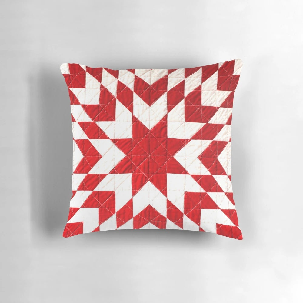 Close-up of a beautiful handmade red and white patchwork quilt pillow with a traditional lone star pattern.