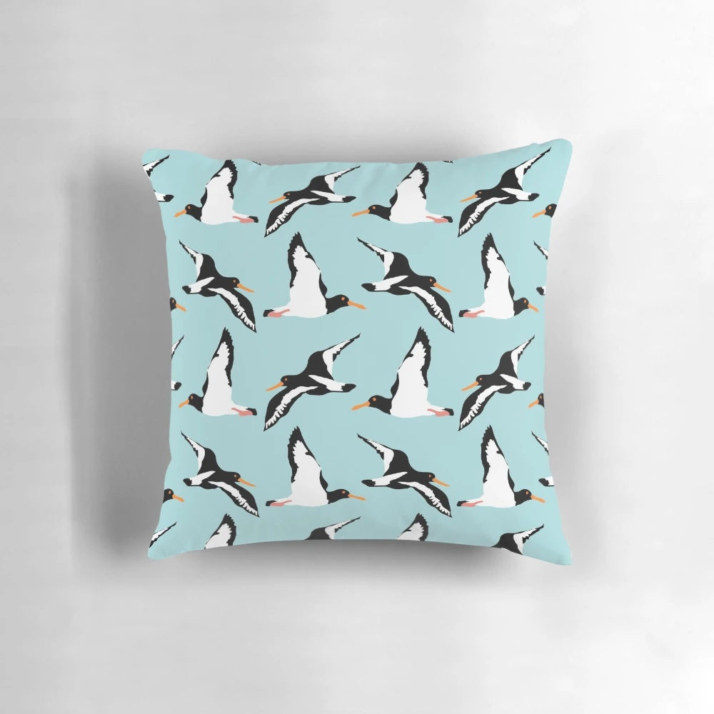Oyster catcher pattern decorative pillow with black and white bird design on a blue background